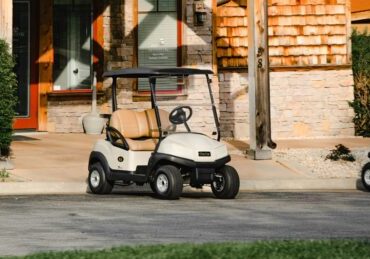 white and black golf cart parked near brown concrete building during daytime